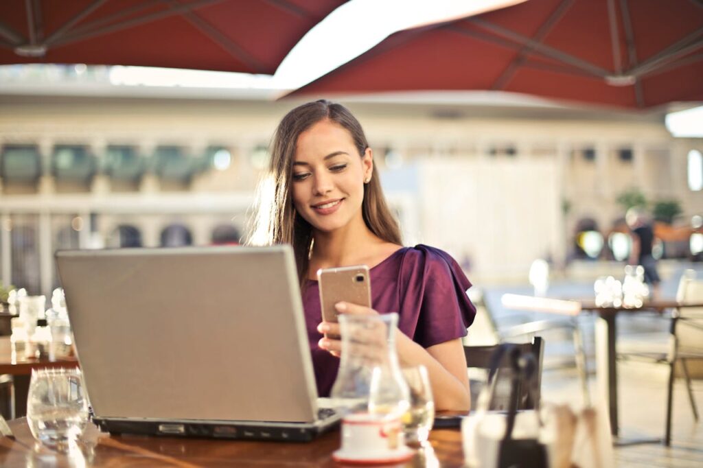 pexels photo 826349 Woman enjoying remote work at a café, using a laptop and smartphone.